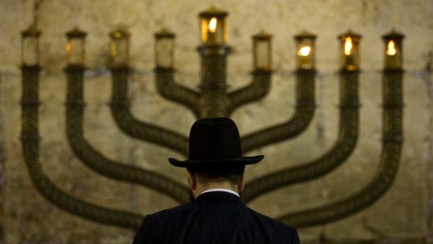 An Jewish man stands in front a menorah on the third eve of Hanukkah, at the Western Wall, in Jerusalem's old city.