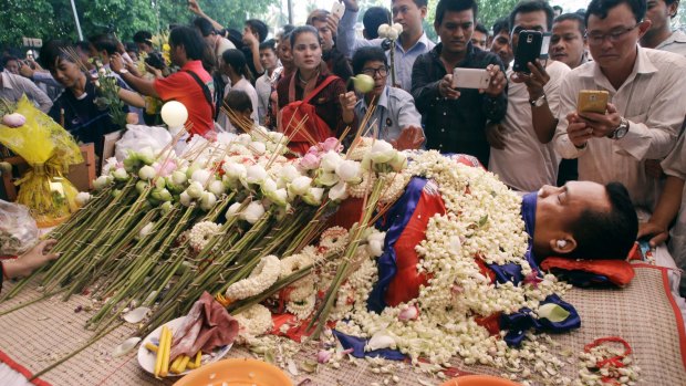 The body of government critic Kem Ley is covered by the Cambodian flag and flowers at a funeral ceremony in Phnom Penh.