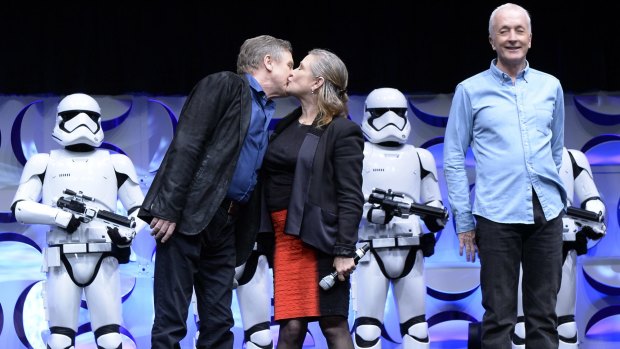 Cast members of the original <i>Star Wars</i> film Mark Hamill (left) and Carrie Fisher kiss as Anthony Daniels looks on during the kick-off event of Disney's Star Wars Celebration 2015.