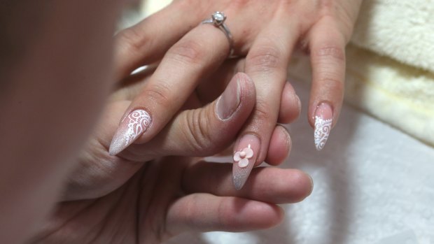 Jonny Diep Pham makes acrylic flowers bloom on his client's fingernails.