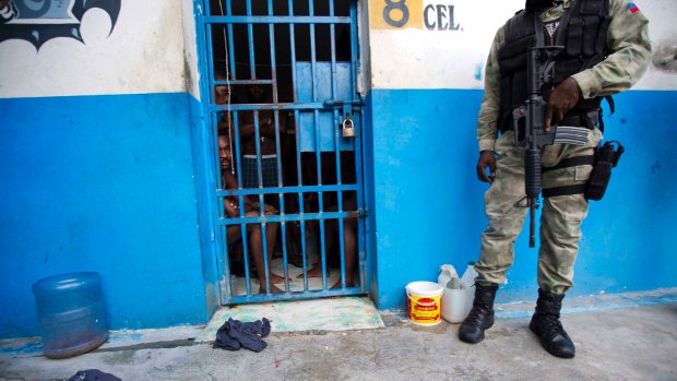 A police officer stands outside a room of inmates after a prison break at the Civil Prison in the coastal town of Arcahaiea, Haiti.