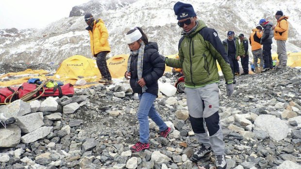 A man helps an injured woman after she is checked by a doctor at the International Mount Guide camp at Everest Base Camp on Sunday.
