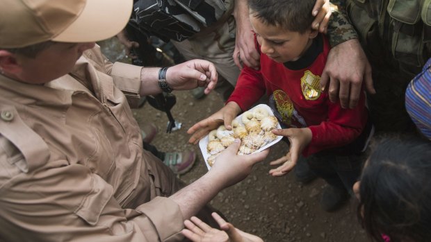 Children reach out for sweets distributed by a Russian soldier in Maarzaf, Syria.