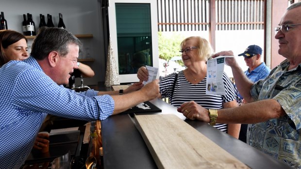 Queensland Opposition Leader Tim Nicholls (left) looks at residents' power bills as he visits Enzo's On The Beach Cafe in Hervey Bay.