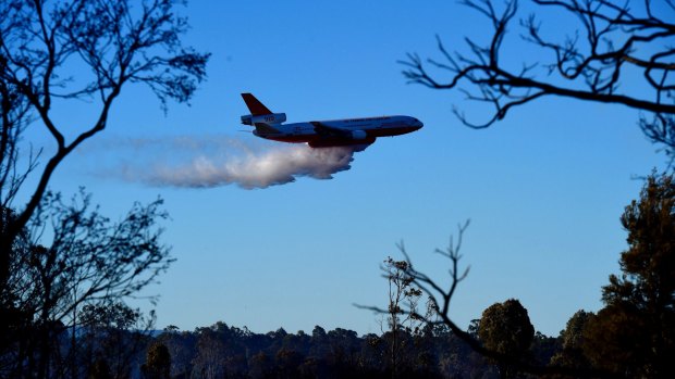 The rural fire service's DC-10 water bombing aircraft dumps its load along Cranebrook Road.