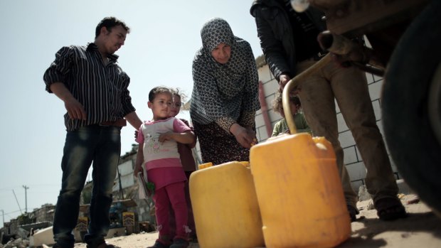 A Palestinian family fill plastic containers with drinking water they bought from a vendor in Khan Younis refugee camp, in the southern Gaza Strip.  