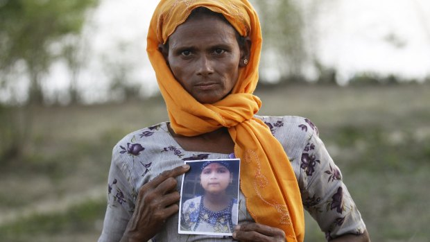 A Rohingya Muslim woman outside Sittwe in Myanmar with a picture of her daughter, who she says is being held by a human trafficker.