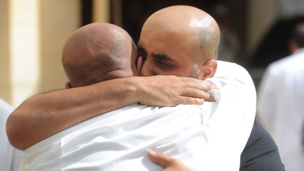 Men comfort each other after a deadly blast claimed by the Islamic State group that struck worshippers attending Friday prayers at a Shiite mosque in Kuwait City.