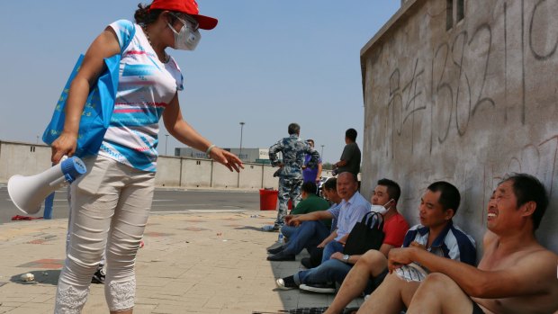 A volunteer calls locals to a concentrated shelter in Tianjin.  