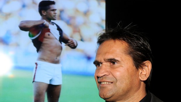 Nicky Winmar in 2013, with the famous picture of him confronting abusive Collingwood fans in 1993.