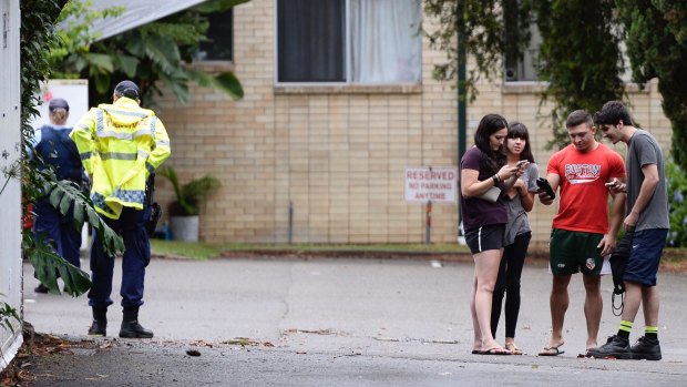 Evacuated residents check their phones as emergency services inspect an unstable unit block on Ewart Street in Marrickville.