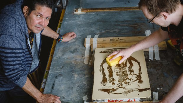 Artist Arone Meeks watches Megalo press studio manager John Hart with a lithograph.