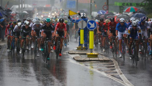 A gendarme signals danger as the pack passes in pouring rain during the second stage of the Tour de France.