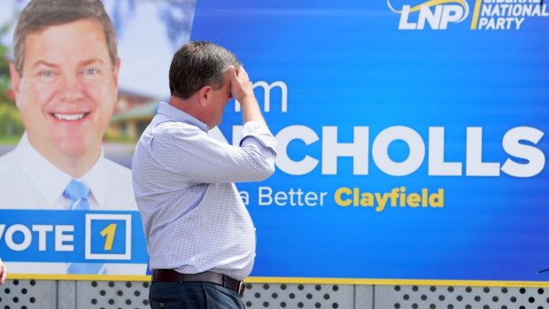 Queensland Opposition Leader Tim Nicholls walks past one of his signs on the last day of the campaign.