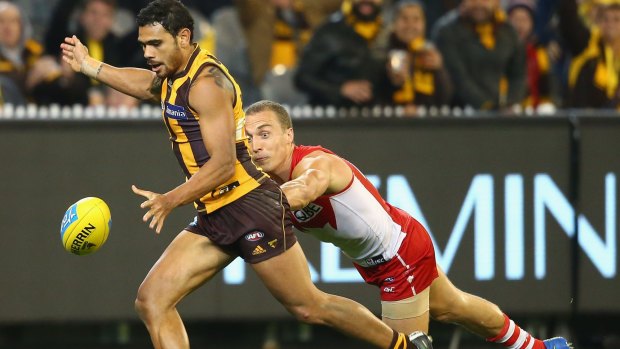 Under pressure: Hawthorn’s Cyril Rioli kicks for goal while being tackled by Sydney's Ted Richards.  