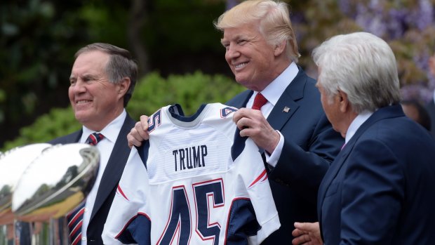 President Donald Trump holds up a New England Patriots jersey presented to him by Patriots owner Robert Kraft, right, and head coach Bill Belichick during a ceremony on the South Lawn of the White House on April 19, 2017.