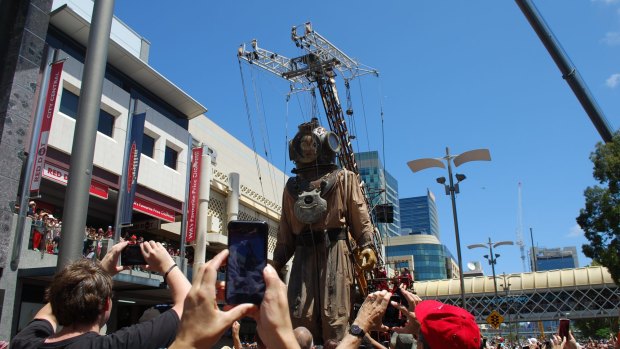 The Giant Diver walks along Wellington Street through a sea of photographers.