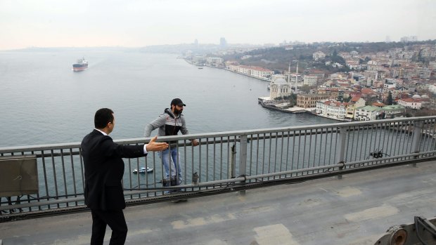 A bodyguard of Turkish President Recep Tayyip Erdogan tries to dissuade Vezir Cakras from jumping off the Bosphorus Bridge in Istanbul on Friday.