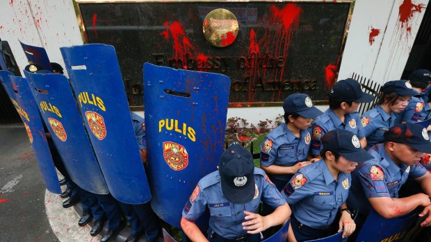 Riot police stand guard in front of the US embassy in Manila after protesters threw red paint as they forced their way closer to the embassy gates.