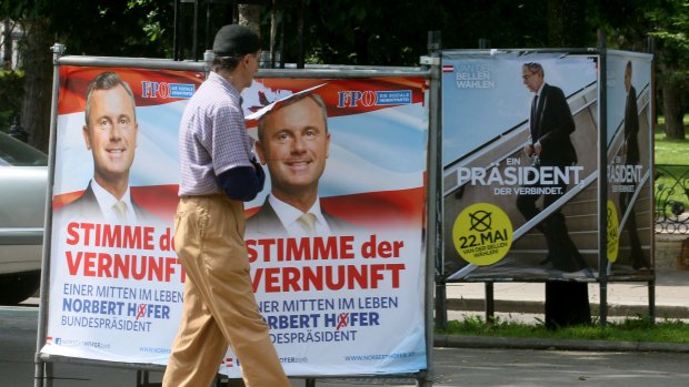 A man walks past election posters of Alexander van der Bellen, candidate for the presidential elections and former head of the Austrian Greens, right, and Norbert Hofer, of Austria's right-wing Freedom Party, left, in Vienna.