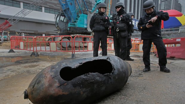 Police officers from explosive ordinance disposal stand next to the bomb at the scene in the Wan Chai district of Hong Kong.