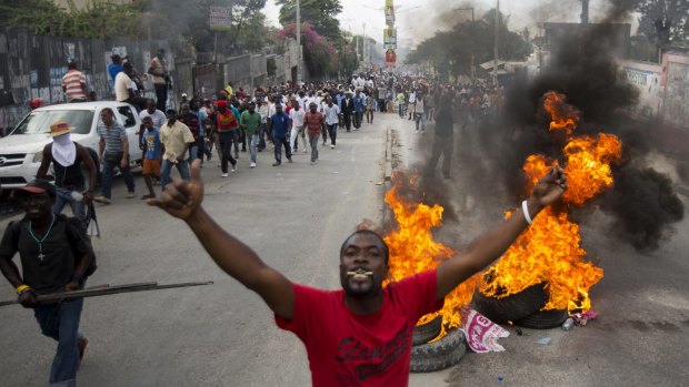 Demonstrators walk past a burning barricade in Port-au-Prince, the Haitian capital.