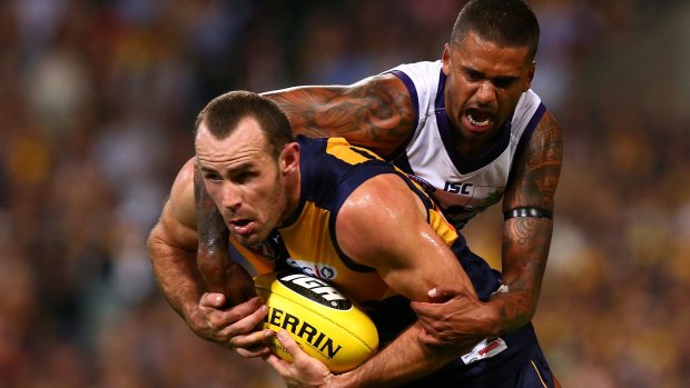 Eagle Shannon Hurn looks to handball while being tackled by Bradley Hill.