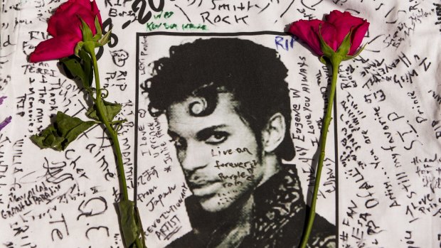 Flowers lay on a T-shirt signed by fans of singer Prince at a makeshift memorial place created outside Apollo Theatre in New York.