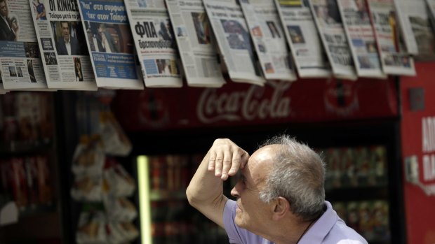 A pedestrian look at newspaper front pages hanging outside a magazine kiosk in central Athens on Thursday. 
