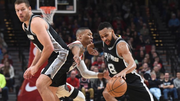 San Antonio Spurs guard Patty Mills drives to the basket  as Portland Trail Blazers guard Damian Lillard defends.