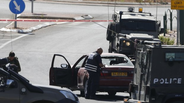 An Israeli policeman takes notes on the car used by 18-year-old Palestinian woman Majd al-Khudour in an attack at the entrance to the settlement of Kiryat Arba, near Hebron, on June 24. Two people were injured by the car and Khudour was killed.