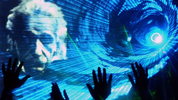 Chinese physicists wave as an image of Albert Einstein is projected during a laser show at a telecommunications company in Shanghai in 2005.