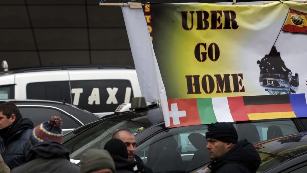 Taxi drivers on strike stand next to their cars as they demonstrate in Paris. 