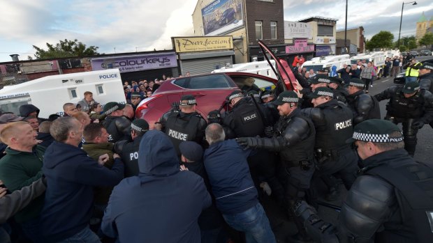 Nationalists join police officers in an attempt to free a young girl trapped underneath a car after an alleged loyalist drove reversed at high speed towards the controversial Ardoyne flashpoint on Monday. 