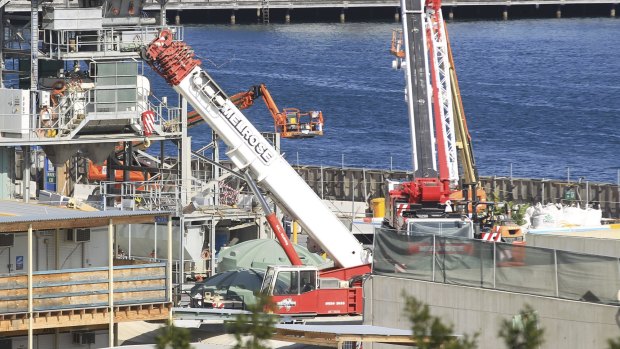 Construction workers gather at the Barangaroo building development following an accident this morning involving a worker who was severely injured on the site: 
