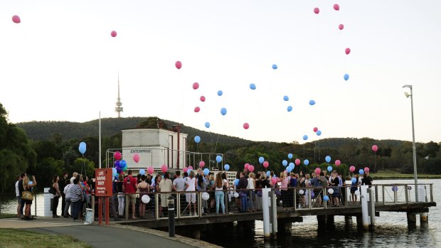 Family and friends release balloons from the jetty near the National Museum of Australia to pay their respects to Cathy Marsh, who died in a car accident.