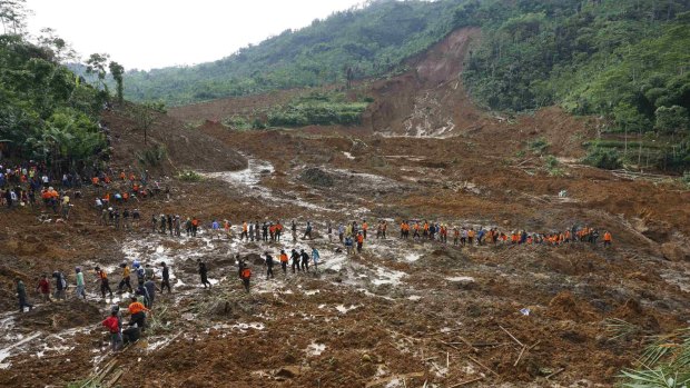 Search for survivors: Indonesian soldiers and rescue team members walk through the mud.