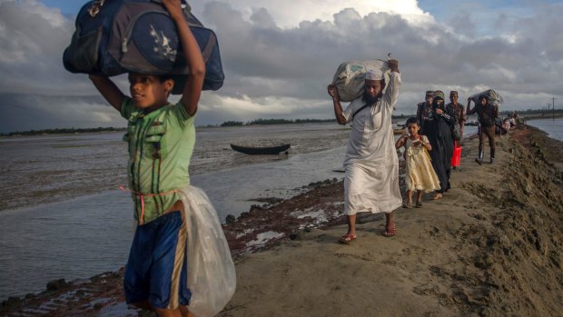 Newly arrived Rohingya Muslims, who crossed over from Myanmar into Bangladesh, walk with their belongings towards the nearest refugee camp at Teknaf, Bangladesh.