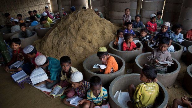 Rohingya children attend class amid material stocked for constructing latrines in Balukhali refugee camp, Bangladesh.