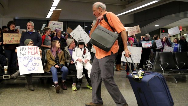 Travellers arriving  at the international gate of  Minneapolis-St Paul International Airport are greeted by protesters.