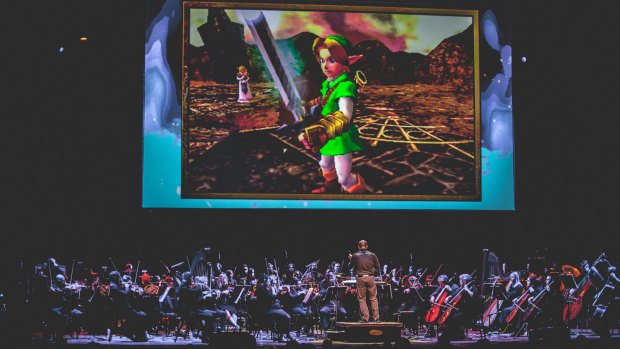 Recorded gameplay is projected above the orchestra and choir.