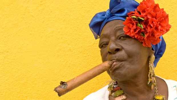 A Cuban woman, in traditional colonial costume, with a famous Cuban cigar in Old Havana.