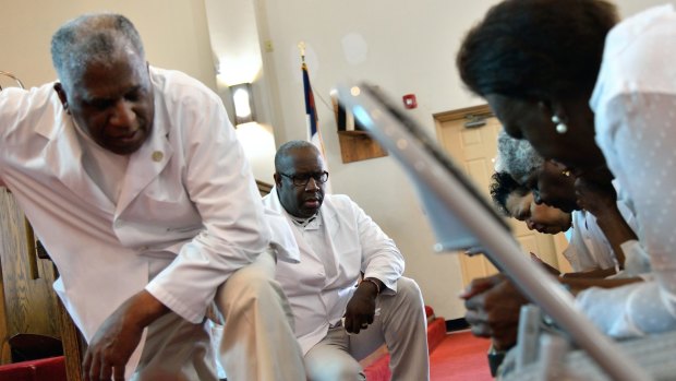 Pastor Jerry Colbert, 64, (left) listens to the prayers of members of a Singing and Praying Band group at the Hall United Methodist Church in Glen Burnie, Maryland.
