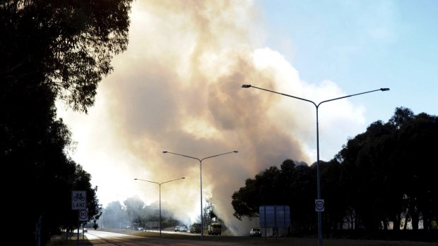 Smoke plumes rise into the sky from the grass fire on Ginninderra Drive at Kaleen.