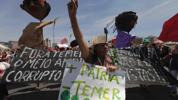 A demonstrator carries a poster written in Portuguese "More Motherland, Less Temer", during protest after an Independence Day military parade in Brasilia.