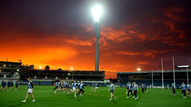 Geelong football team train under the sunset and new lights at Simonds Stadium. 