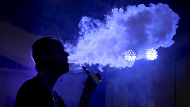 An exhibitor staff member uses an electronic cigarette at Beijing International Vapor Distribution Alliance Expo in July 2015. 