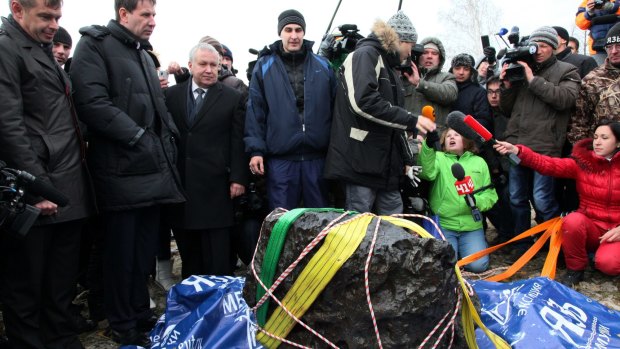People look at what scientists believe to be a chunk of the Chelyabinsk meteor, which exploded over Russia in 2013.