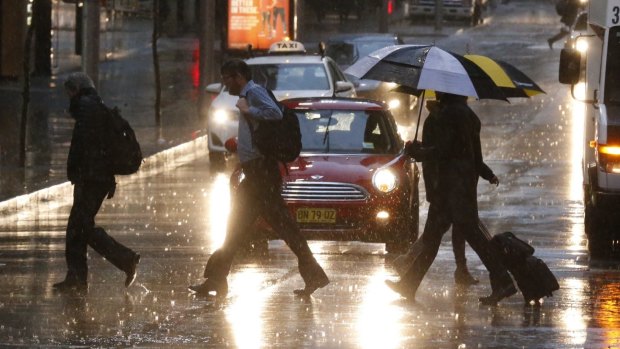 Pedestrians make their way through the wet streets of Sydney on Monday morning.