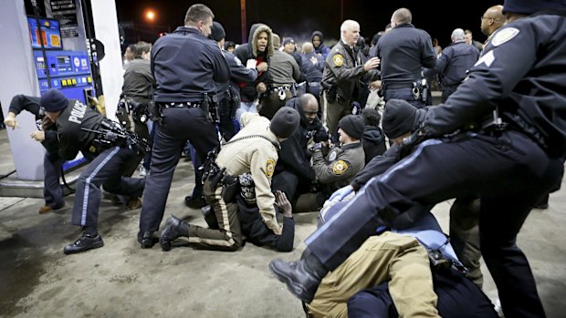 Police attempt to control an angry crowd at the scene of the shooting.